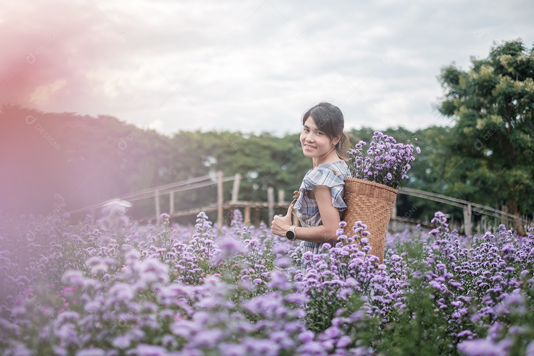Feliz turista de vestido azul desfruta de Margaridas roxas.
