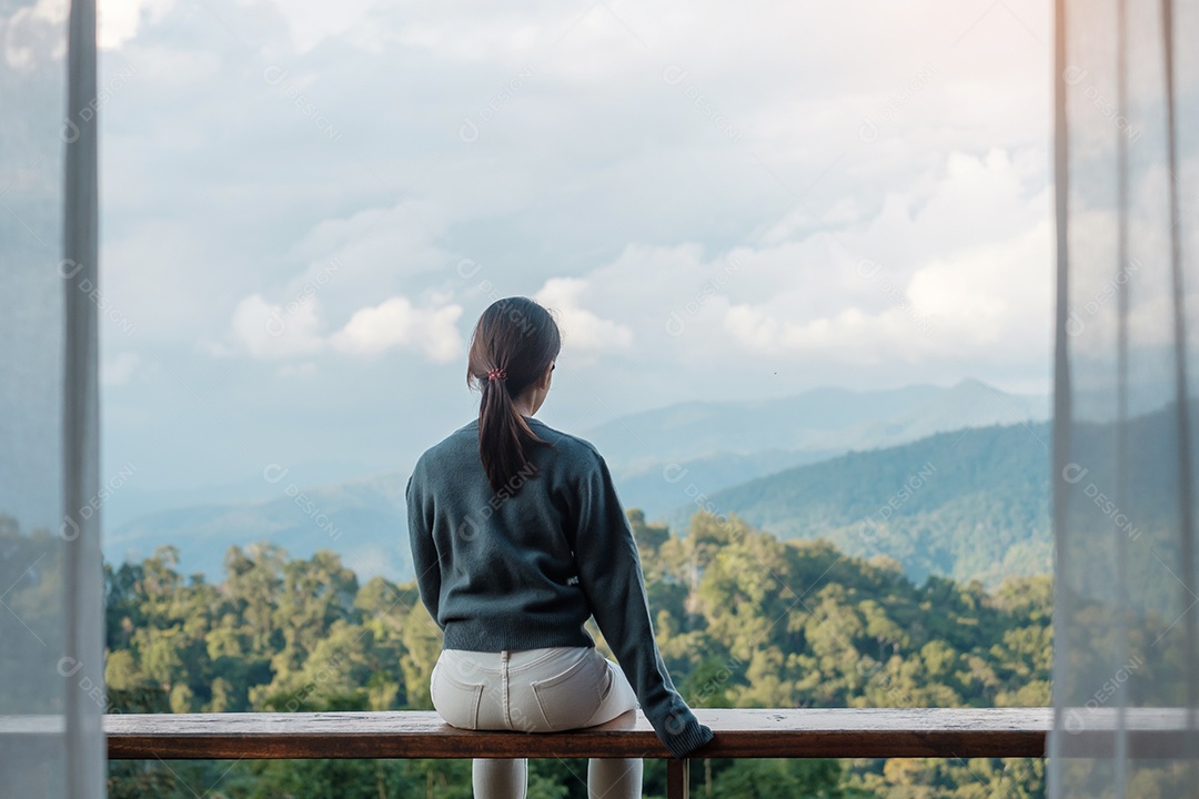 Mulher feliz relaxando e olhando a vista para a montanha no campo.