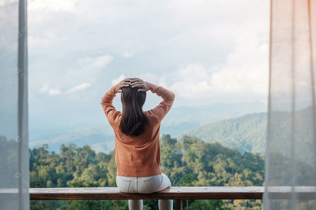 Mulher feliz relaxando e olhando a vista para a montanha no campo.