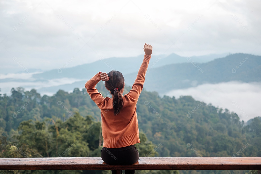 Mulher feliz relaxando e olhando a vista para a montanha no campo.