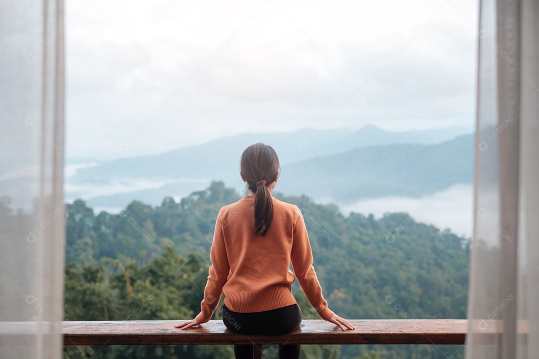 Mulher feliz relaxando e olhando a vista para a montanha no campo.