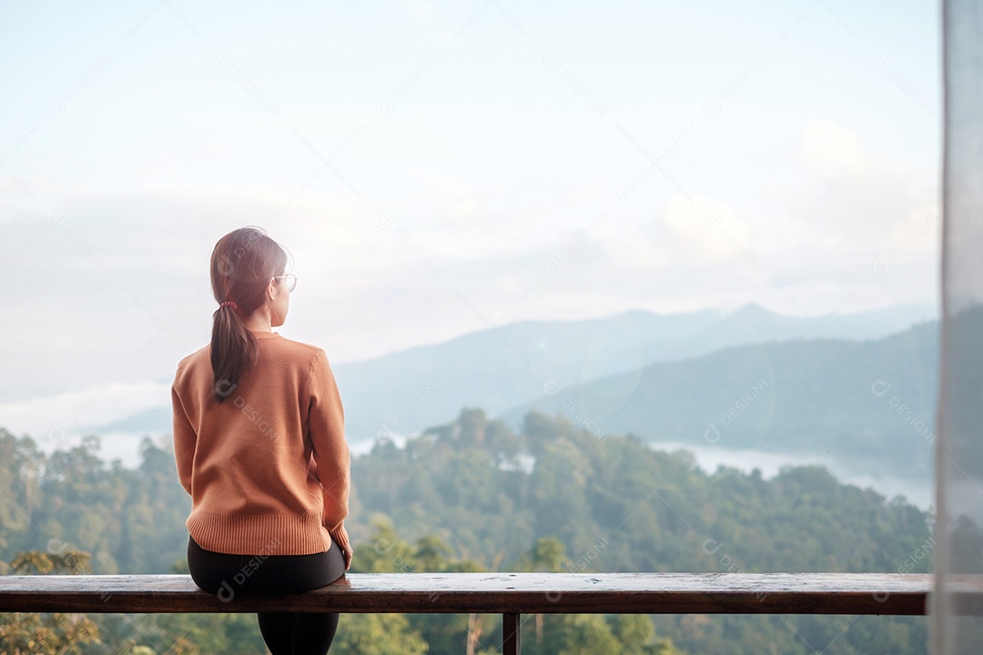 Mulher feliz relaxando e olhando a vista para a montanha no campo.