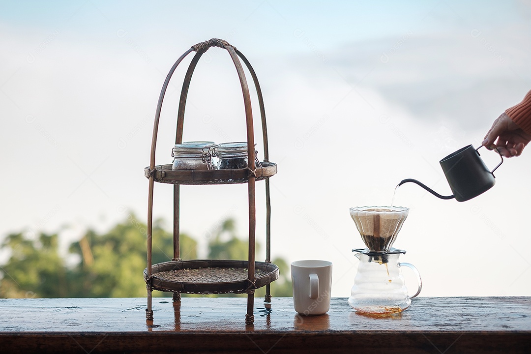 Mão derramando água quente durante a fabricação de café arábica por vintage.