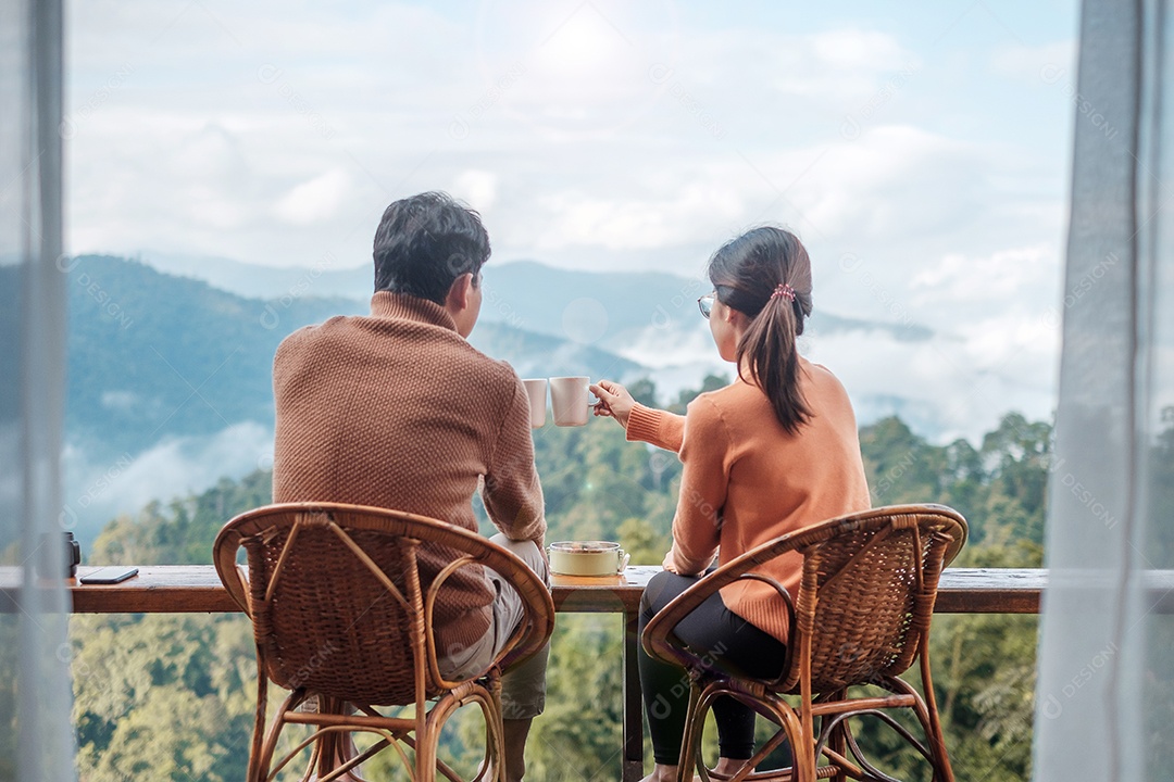 Casal turista tomando café e tomando café da manhã contra o monte.
