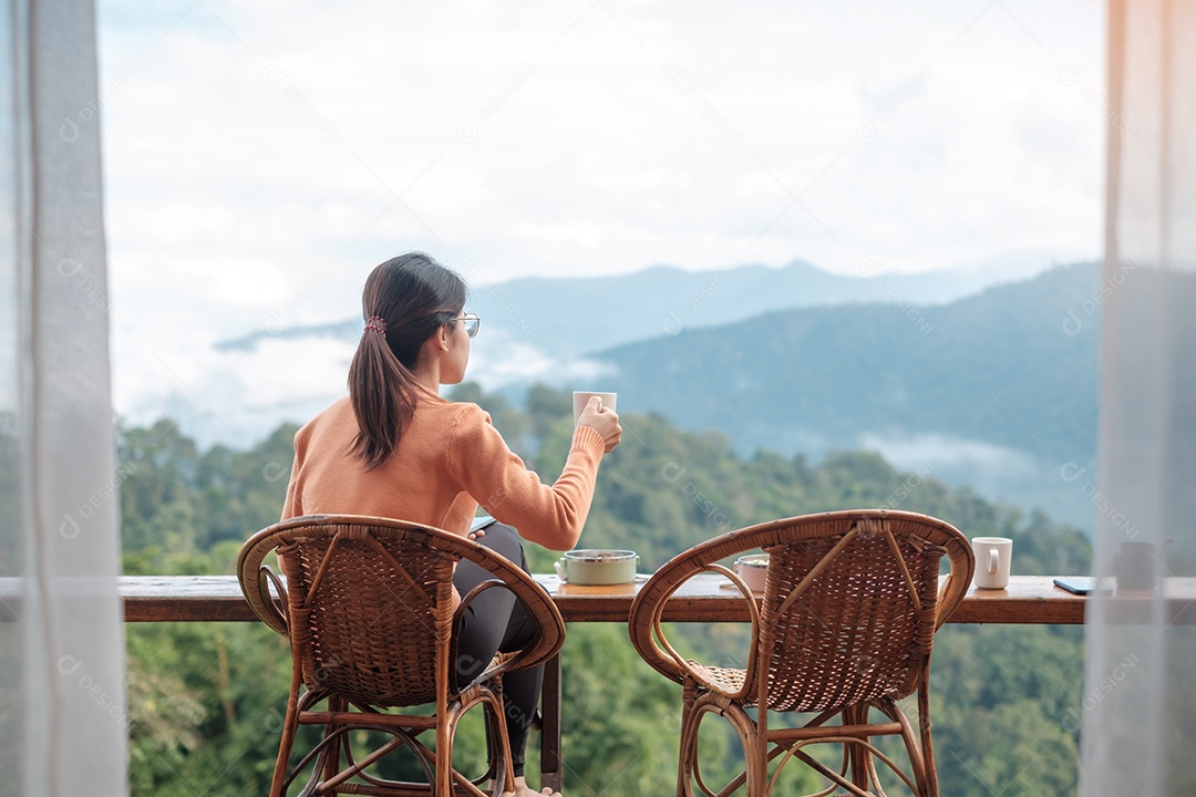 Mulher feliz tomando café e tomando café da manhã contra a montanha.