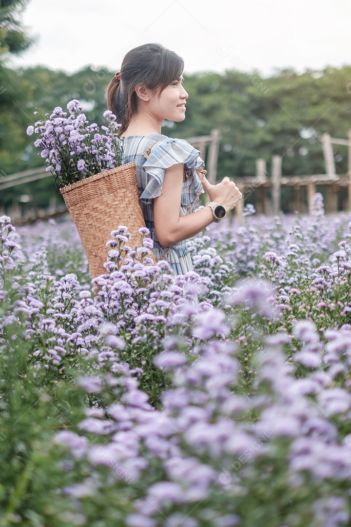 Feliz turista de vestido azul desfruta de Margaridas  roxas.