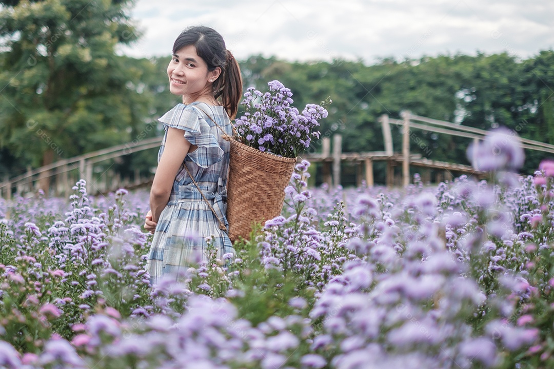 Feliz turista de vestido azul desfruta de Margaridas  roxas.
