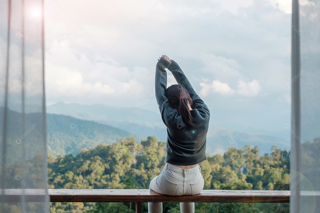 Mulher feliz relaxando e olhando a vista para a montanha no campo.