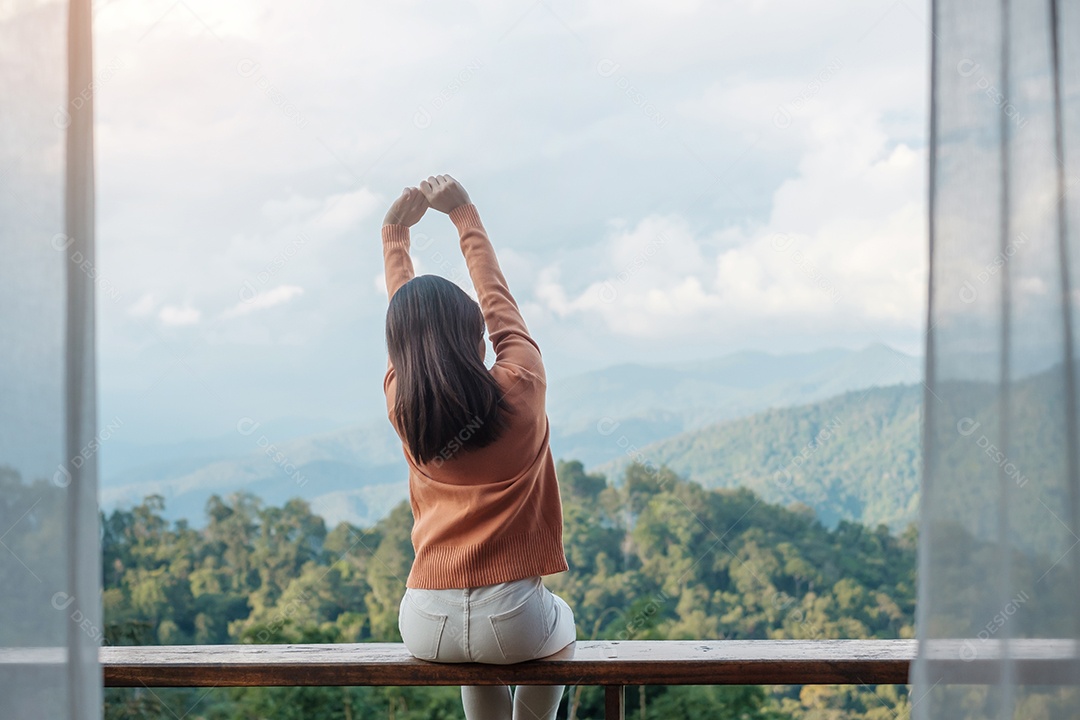 Mulher feliz relaxando e olhando a vista para a montanha no campo.