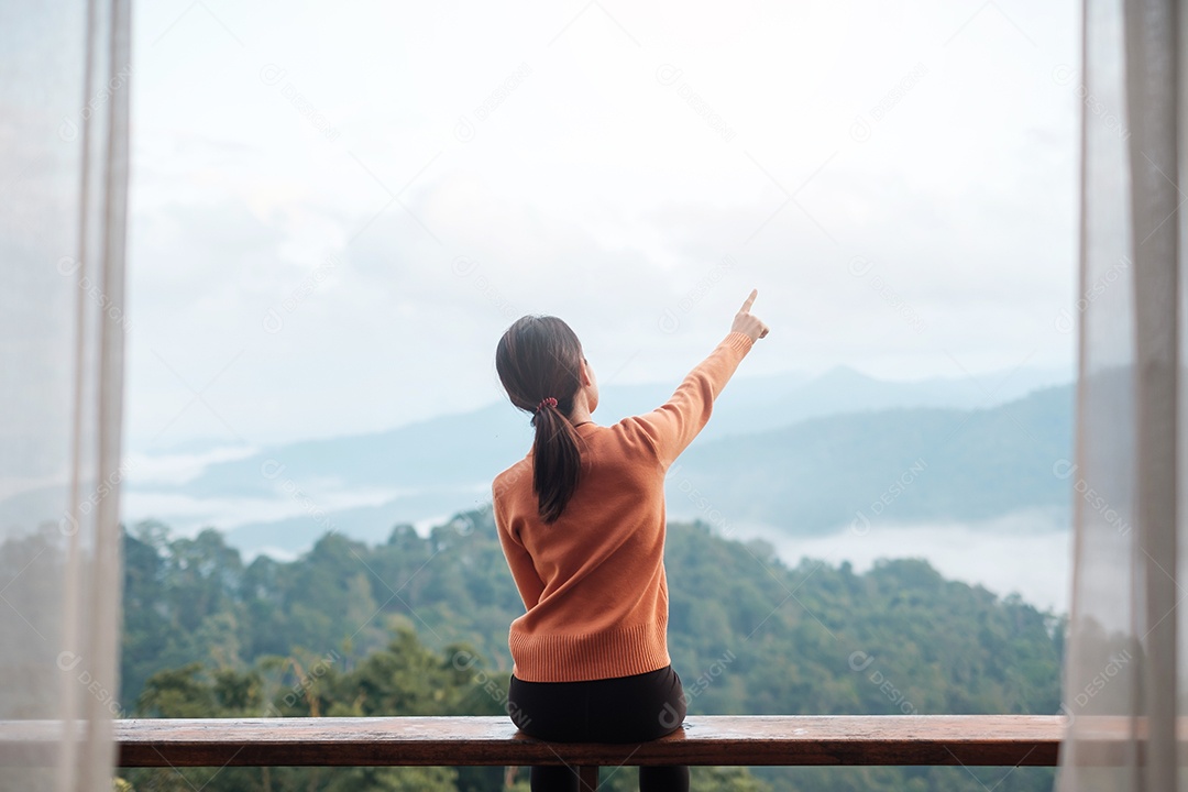 Mulher feliz relaxando e olhando a vista para a montanha no campo.