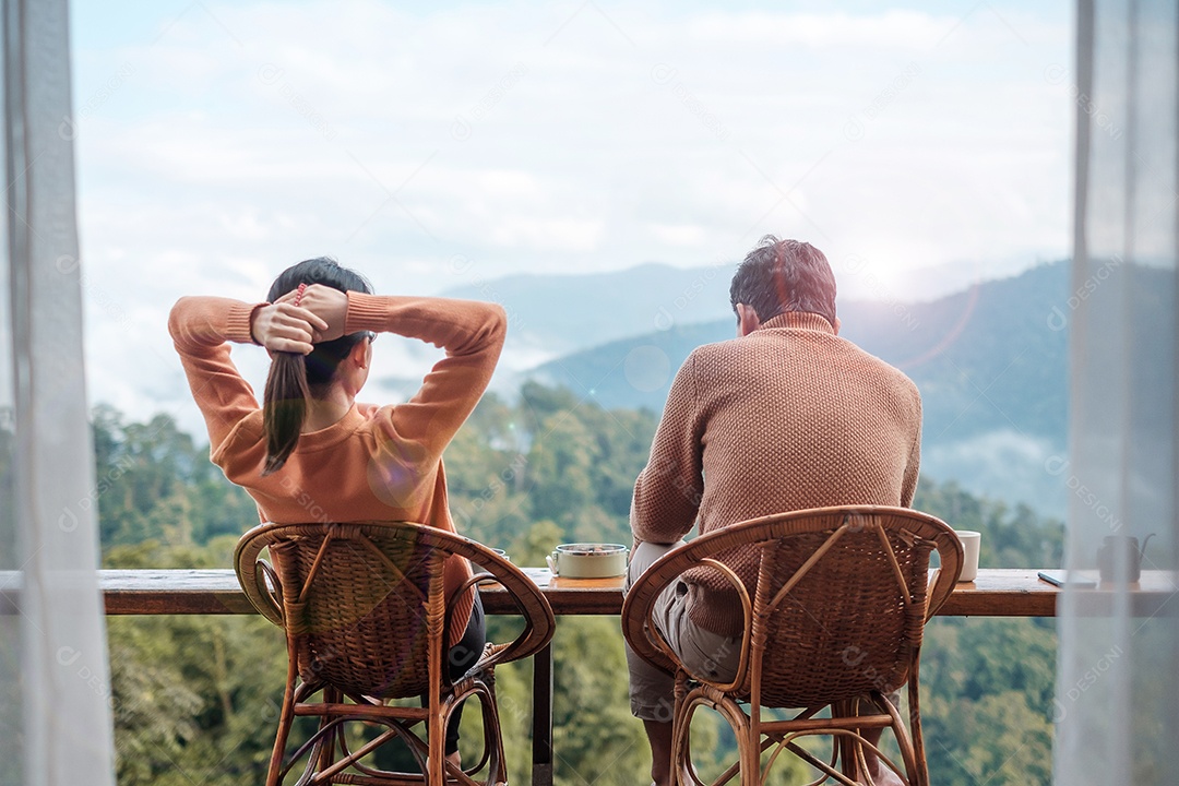 Casal turista tomando café e tomando café da manhã contra o monte.