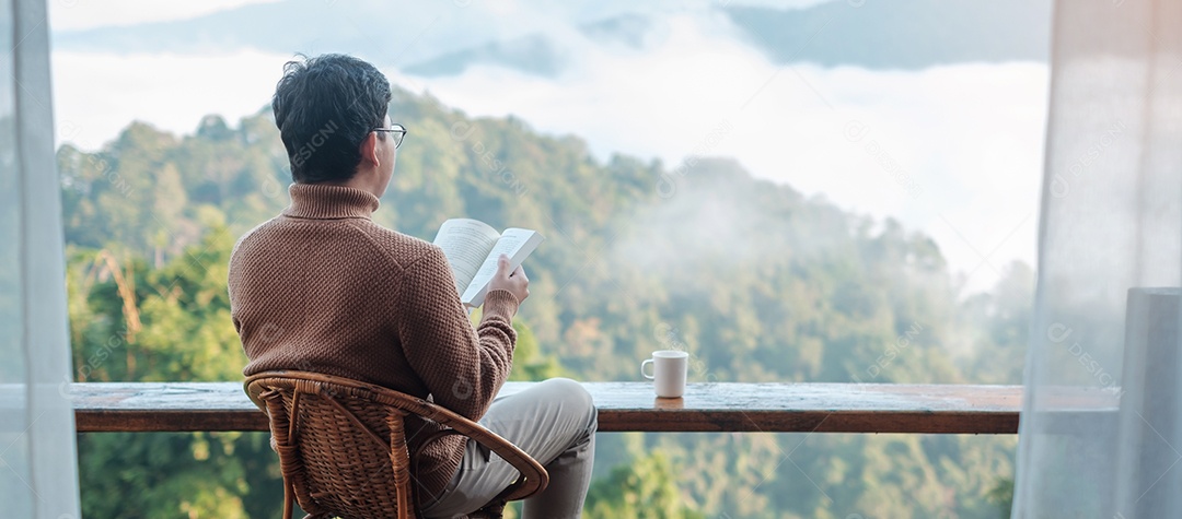 jovem lendo livro perto da janela e olhando a vista para a montanha