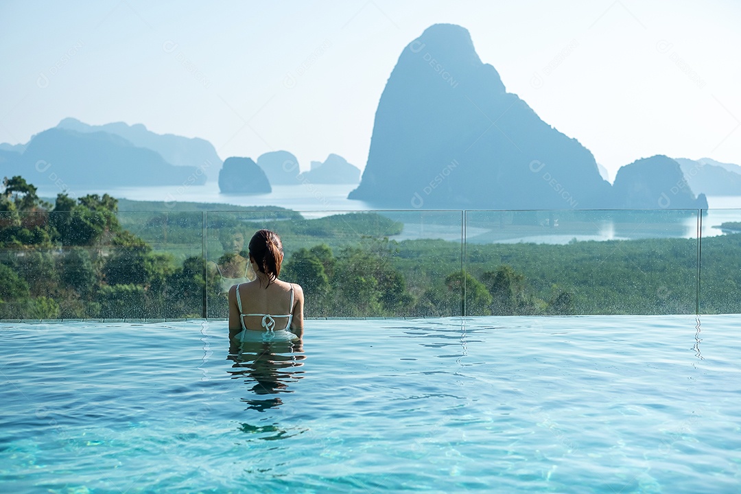 Mulher feliz em maiô branco nadando na piscina de luxo hotel.