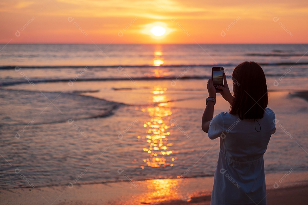 Silhueta de uma jovem feliz tirando foto pelo smartphone.