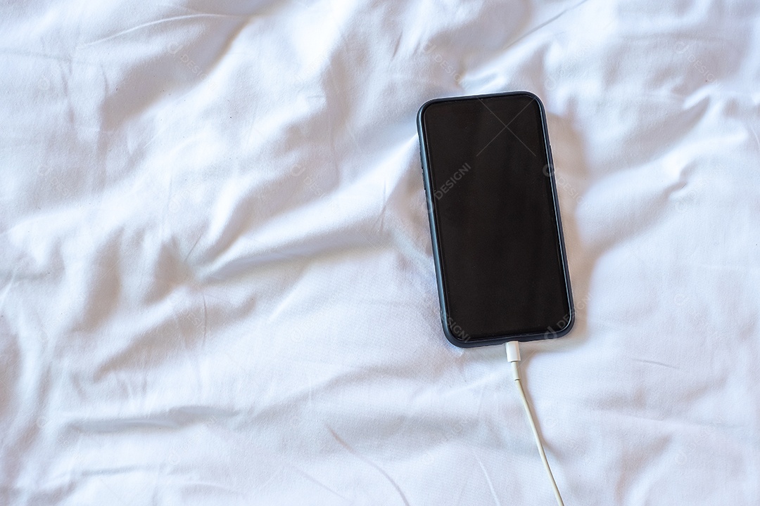 Celular inteligente carregando bateria na cama no quarto em casa.