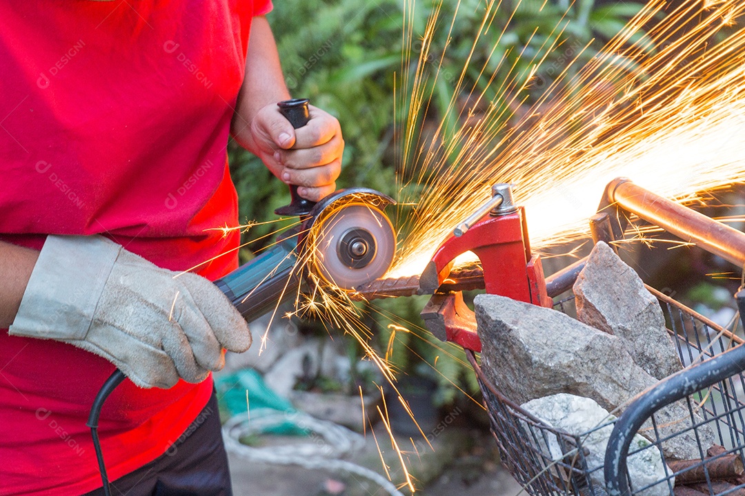 Homem serralheiro usando serra para cortar um pedaço de ferro.