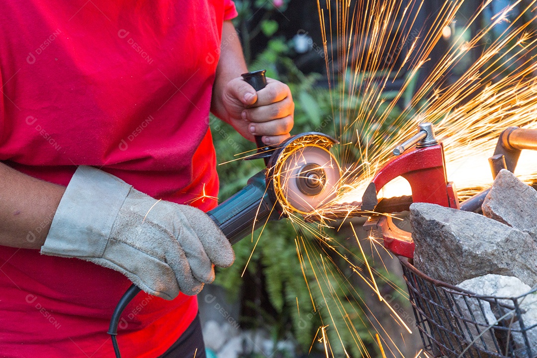 Homem serralheiro usando serra para cortar um pedaço de ferro.