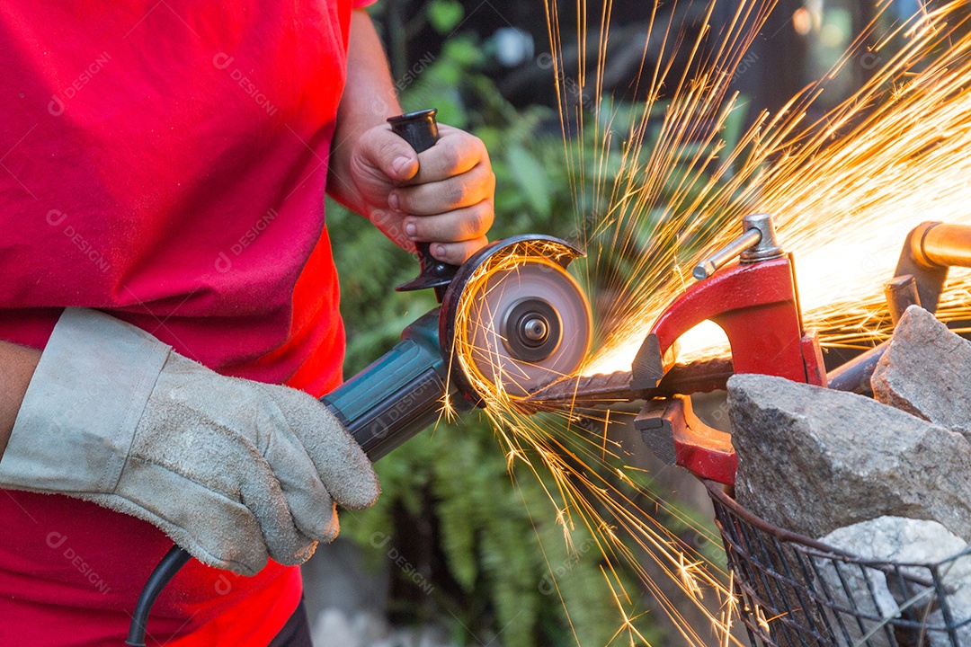 Homem serralheiro usando serra para cortar um pedaço de ferro.