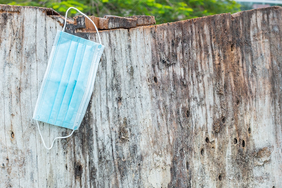 máscara de proteção descartável azul, usada para proteção contra cornavírus, jogada em um tronco de árvore no Rio de Janeiro.