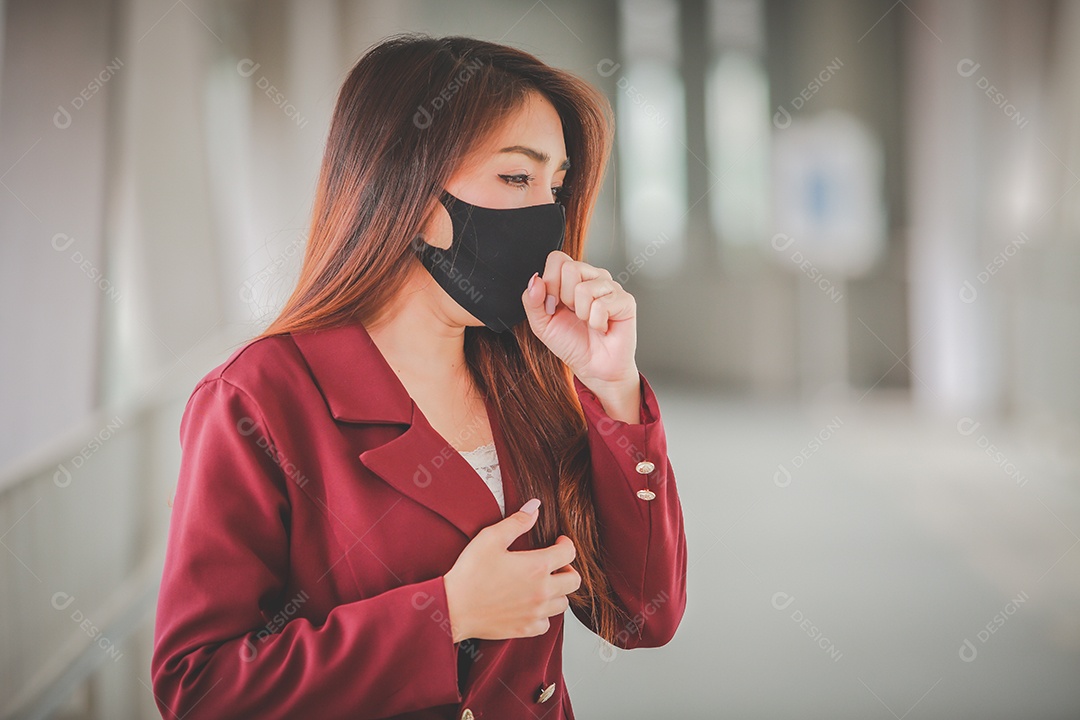 Mulher asiática usando máscara e falando no celular para proteger pm2.5 e tosse com surto de vírus Covid-19 em público.