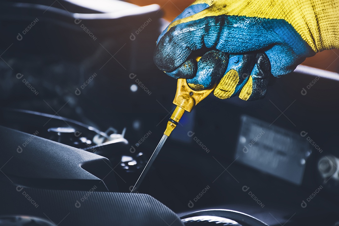 Mão do técnico puxando a vareta de óleo para verificar a lubrificação