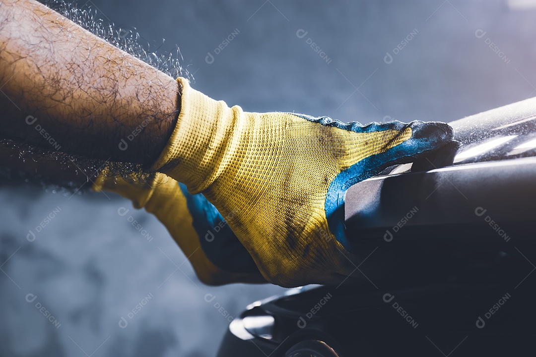 Mão do técnico puxando o capô do carro para manutenção no reparo