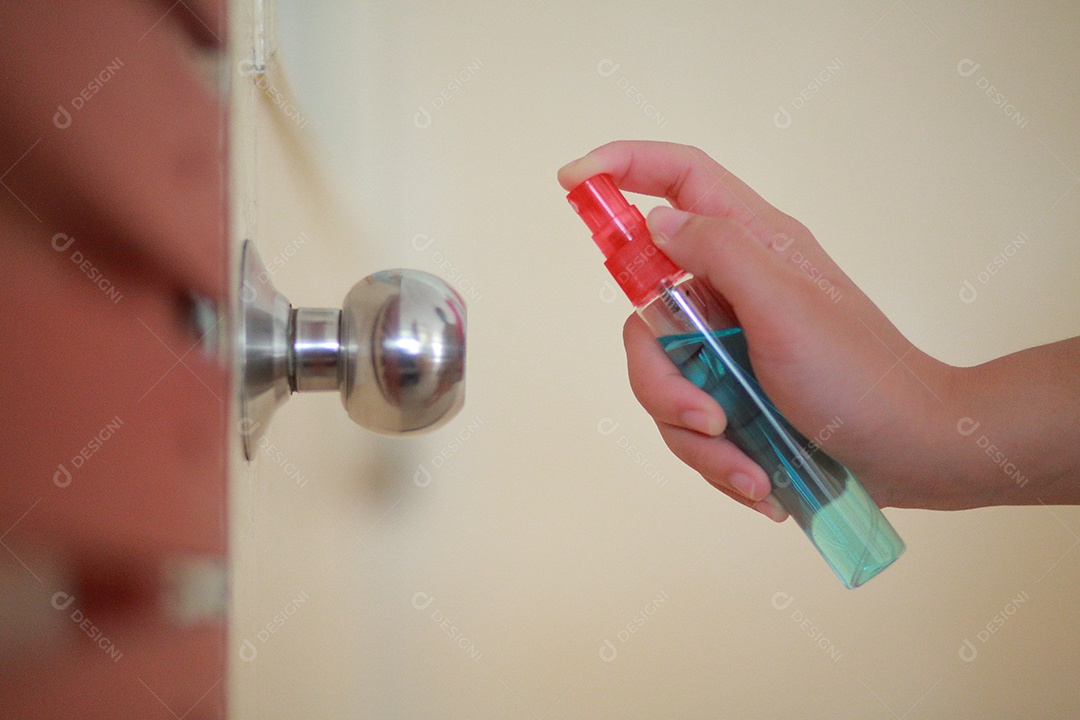 A mão da mulher está pulverizando álcool, spray desinfetante na porta do local de trabalho para segurança, prevenir a infecção do vírus Covid-19, contaminação de germes ou bactérias, limpe as superfícies que são frequentemente tocadas.