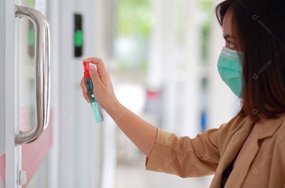 A mão da mulher está pulverizando álcool, spray desinfetante no local de trabalho