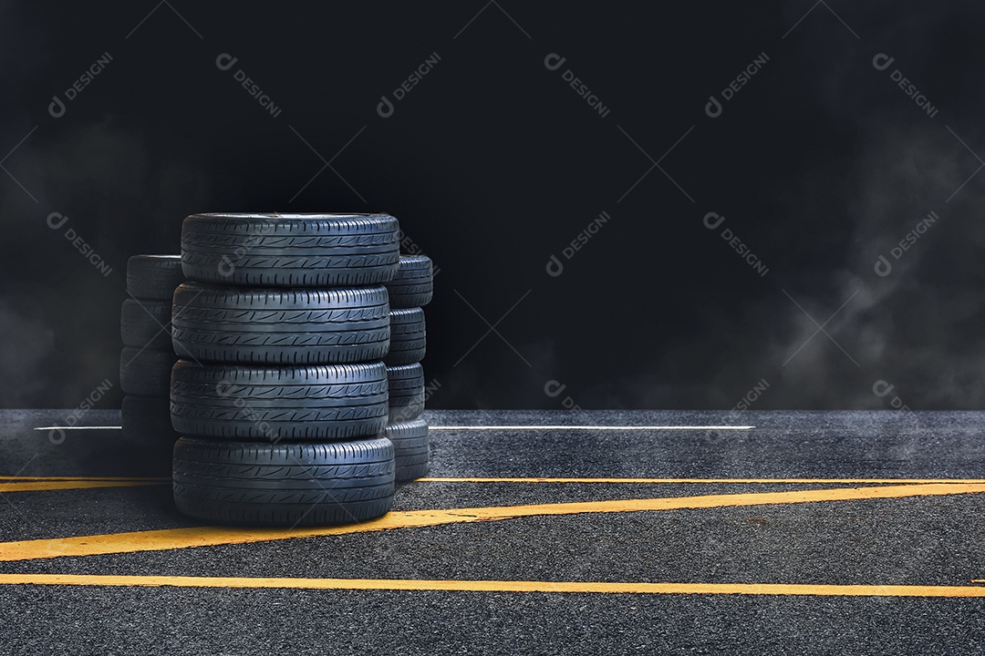 Pilha de pneus na estrada de asfalto com fumaça à noite e costas pretas