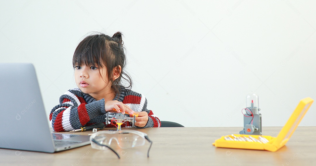 A garotinha asiática construindo carro robótico na aula de ciências