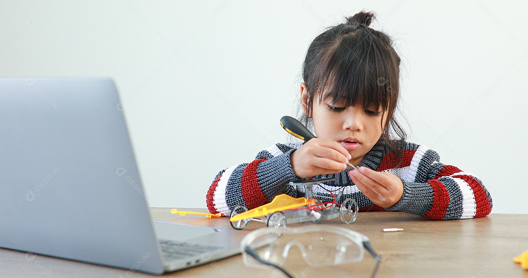 A garotinha asiática construindo carro robótico na aula de ciências