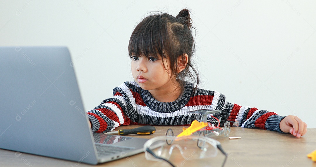A garotinha asiática construindo carro robótico na aula de ciências