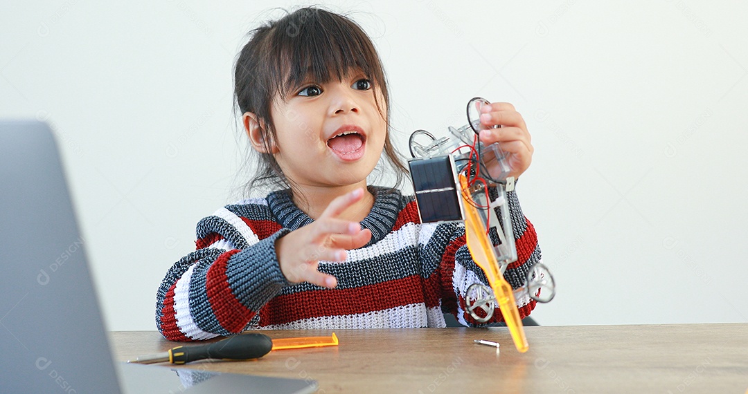 A garotinha asiática construindo carro robótico na aula de ciências