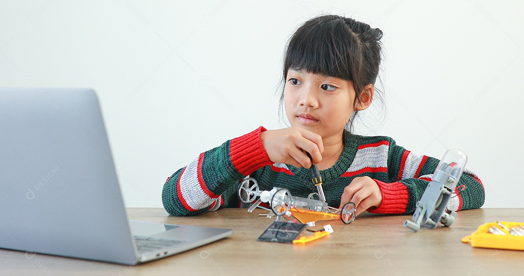 A garotinha asiática construindo carro robótico na aula de ciências