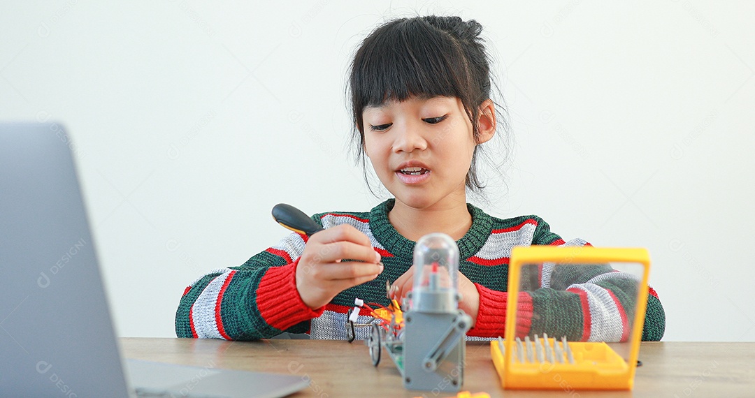 A garotinha asiática construindo carro robótico na aula de ciências