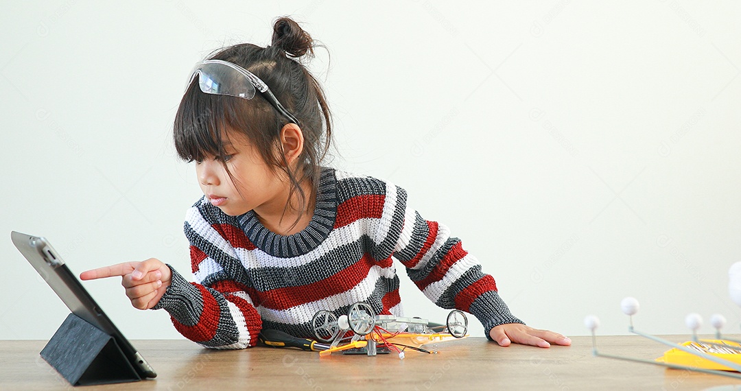 A garotinha asiática construindo carro robótico na aula de ciências