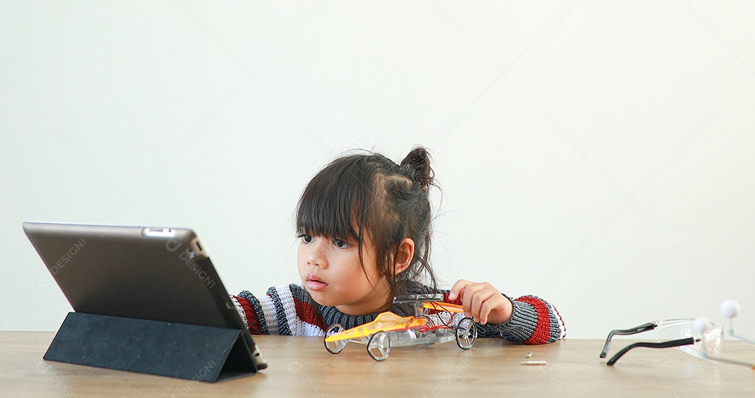 A garotinha asiática construindo carro robótico na aula de ciências