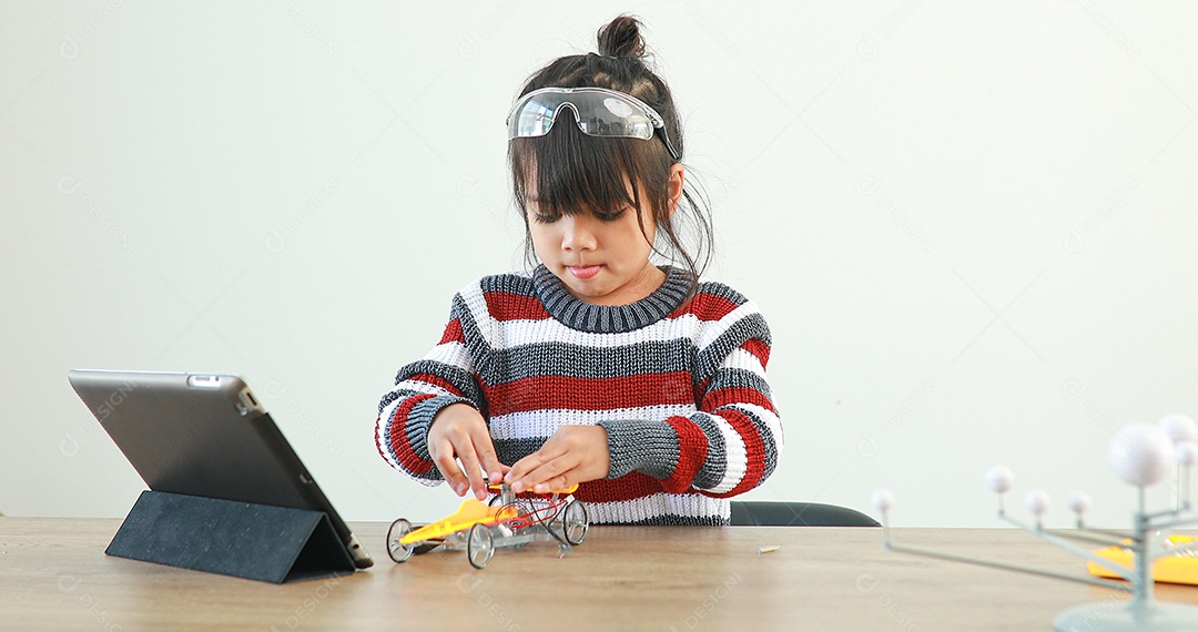 A garotinha asiática construindo carro robótico na aula de ciências