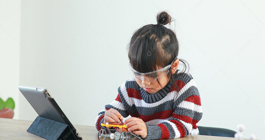 A garotinha asiática construindo carro robótico na aula de ciências