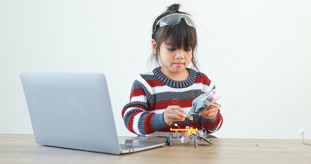 A garotinha asiática construindo carro robótico na aula de ciências