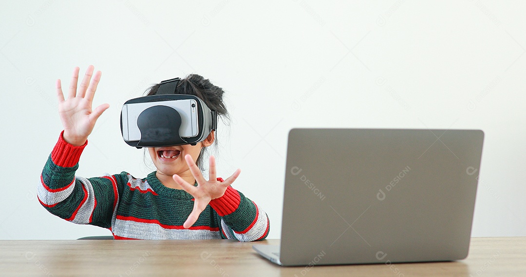 A garotinha vestindo VR sentada na mesa de óculos em casa