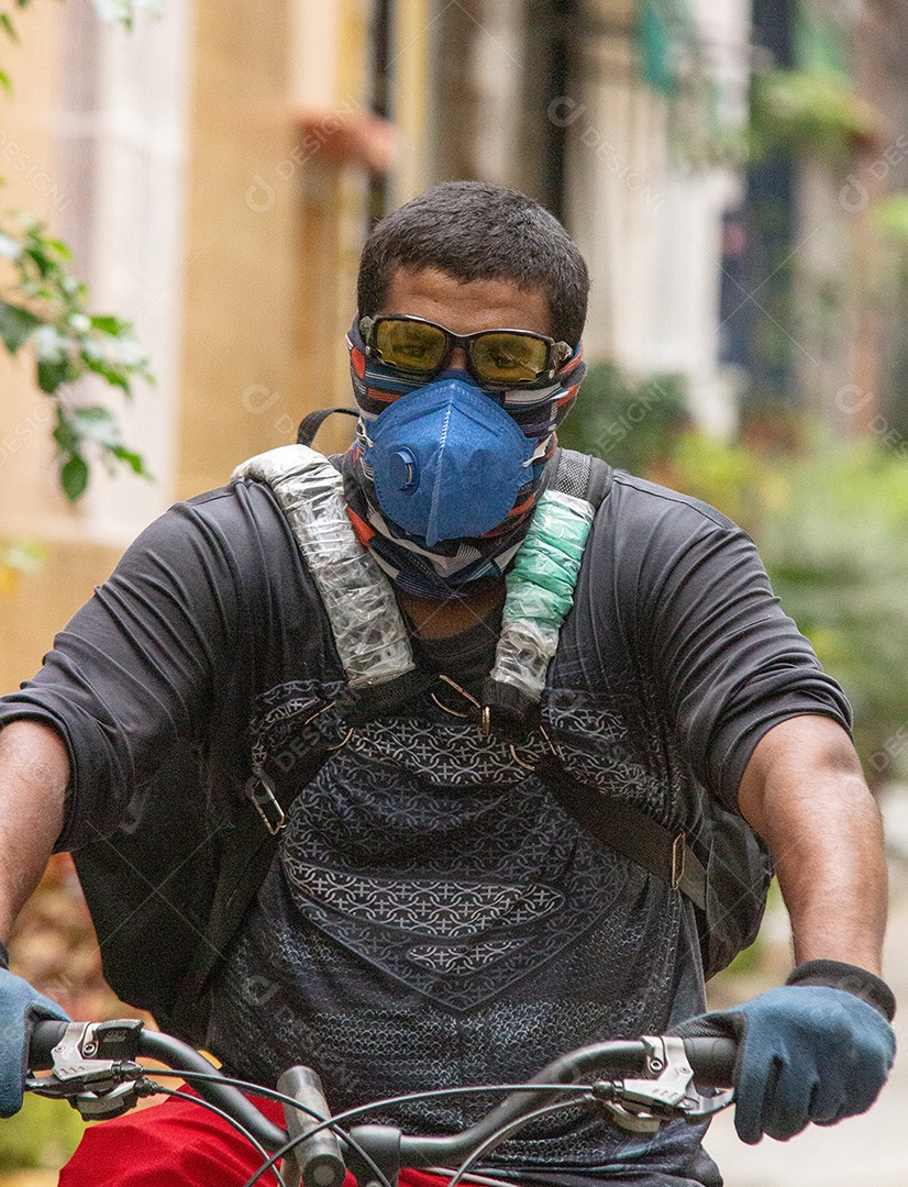 homem negro entregando comida de bicicleta em uma rua do Rio de Janeiro, Brasil.