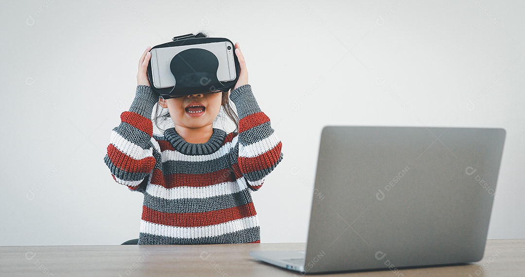 Linda menina criança usando oculos realidade virtual usando notebook