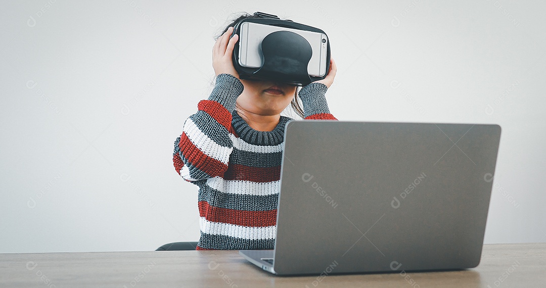 Linda menina criança usando oculos realidade virtual usando notebook