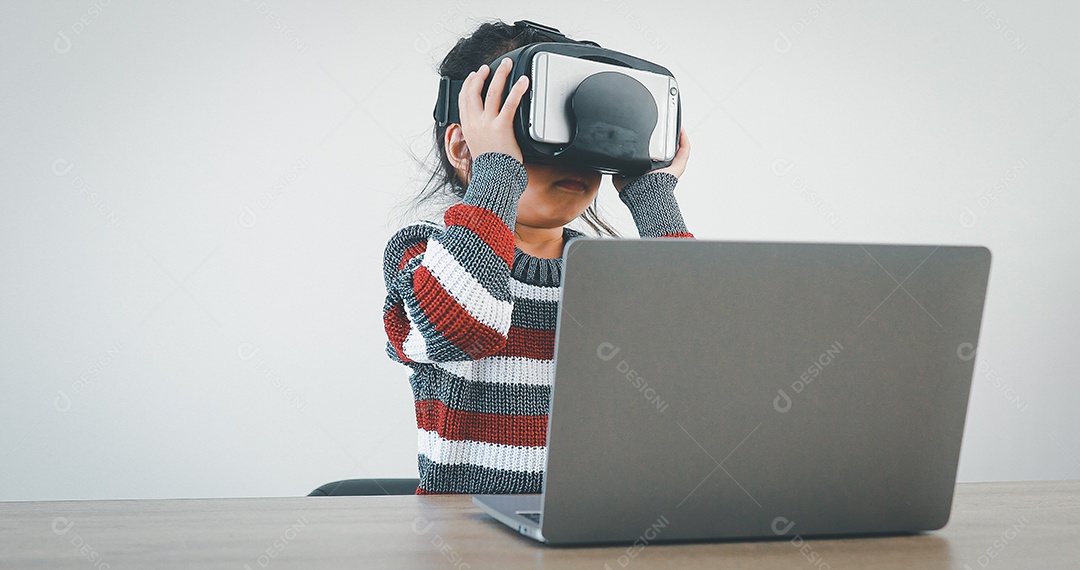 Linda menina criança usando oculos realidade virtual usando notebook