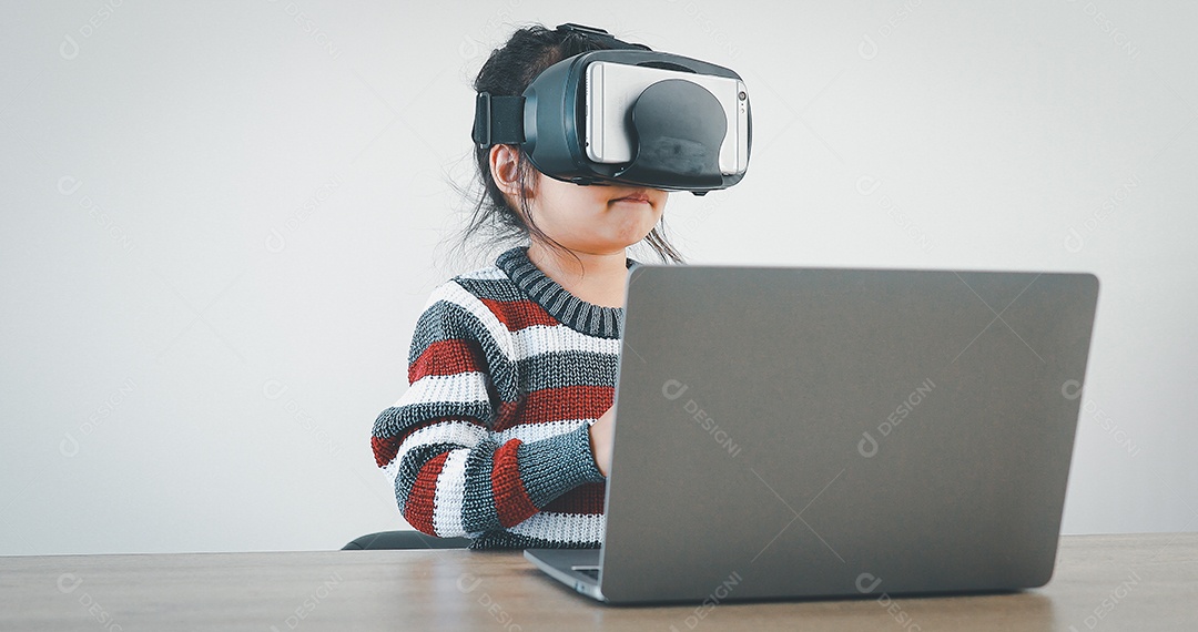 Linda menina criança usando oculos realidade virtual usando notebook