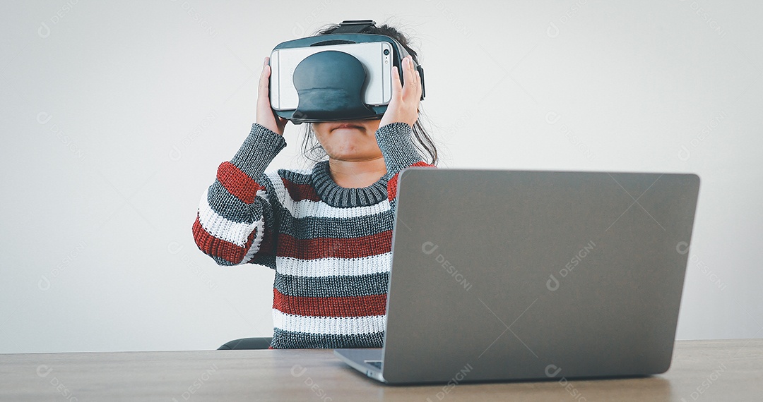 Linda menina criança usando oculos realidade virtual usando notebook