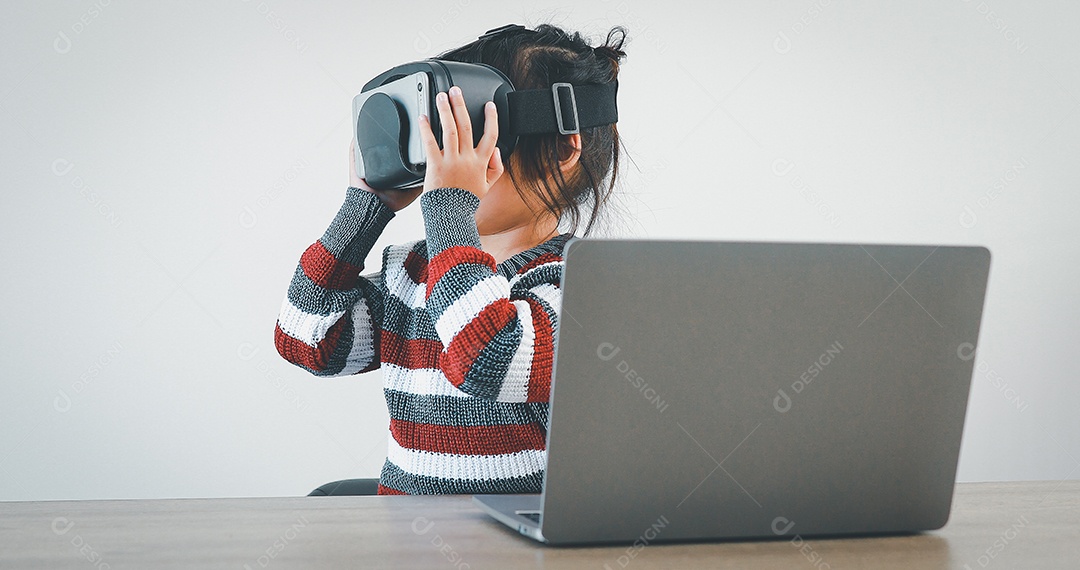 Linda menina criança usando oculos realidade virtual usando notebook