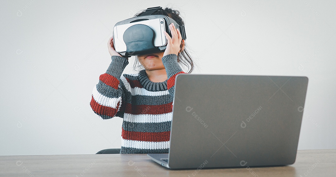 Linda menina criança usando oculos realidade virtual usando notebook