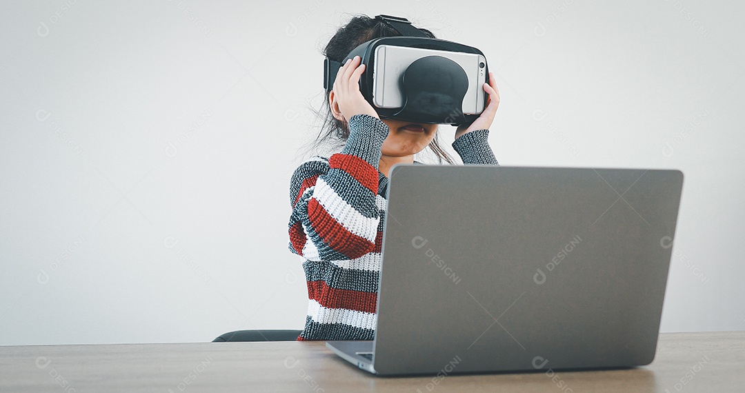 Linda menina criança usando oculos realidade virtual usando notebook